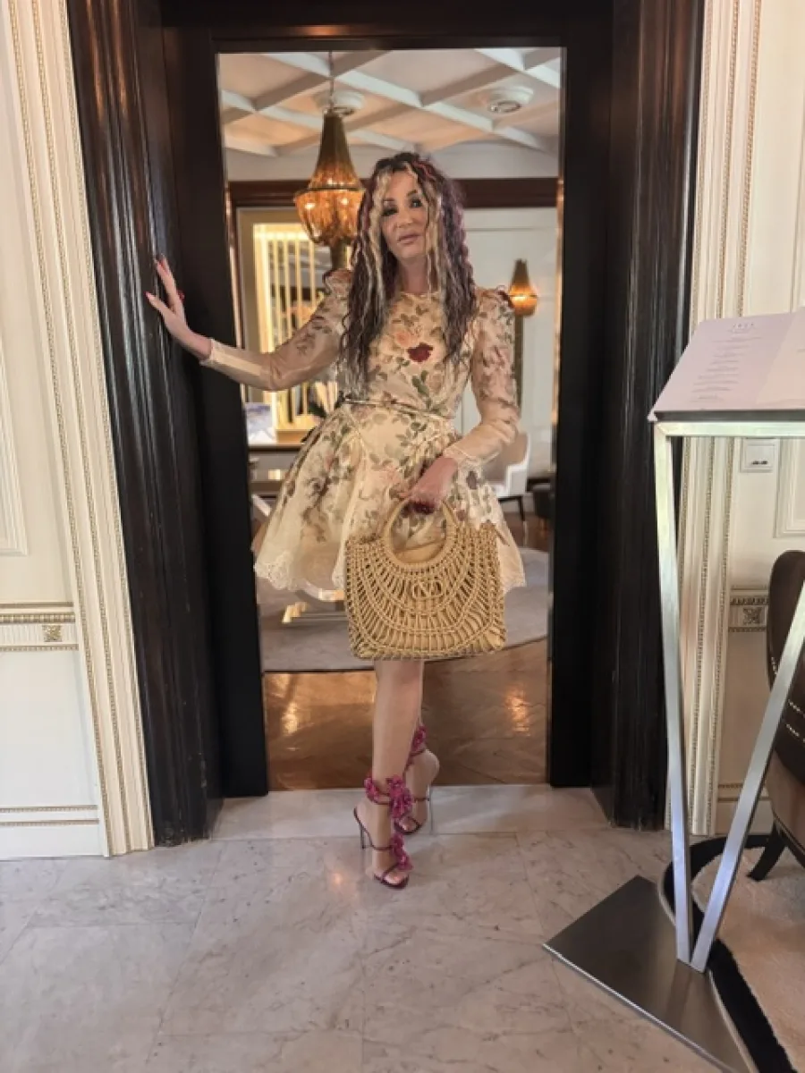 Michaela Hoppe in floralem Kleid mit feiner Strumpfhose und pinkfarbenen offenen High Heels