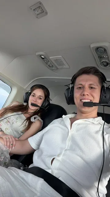 Ein junges Paar sitzt mit Headsets im Flugzeug