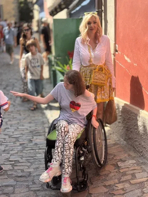 Sarah fährt im Rollstuhl über Prager Kopfsteinpflaster, Michi geht hinter ihr