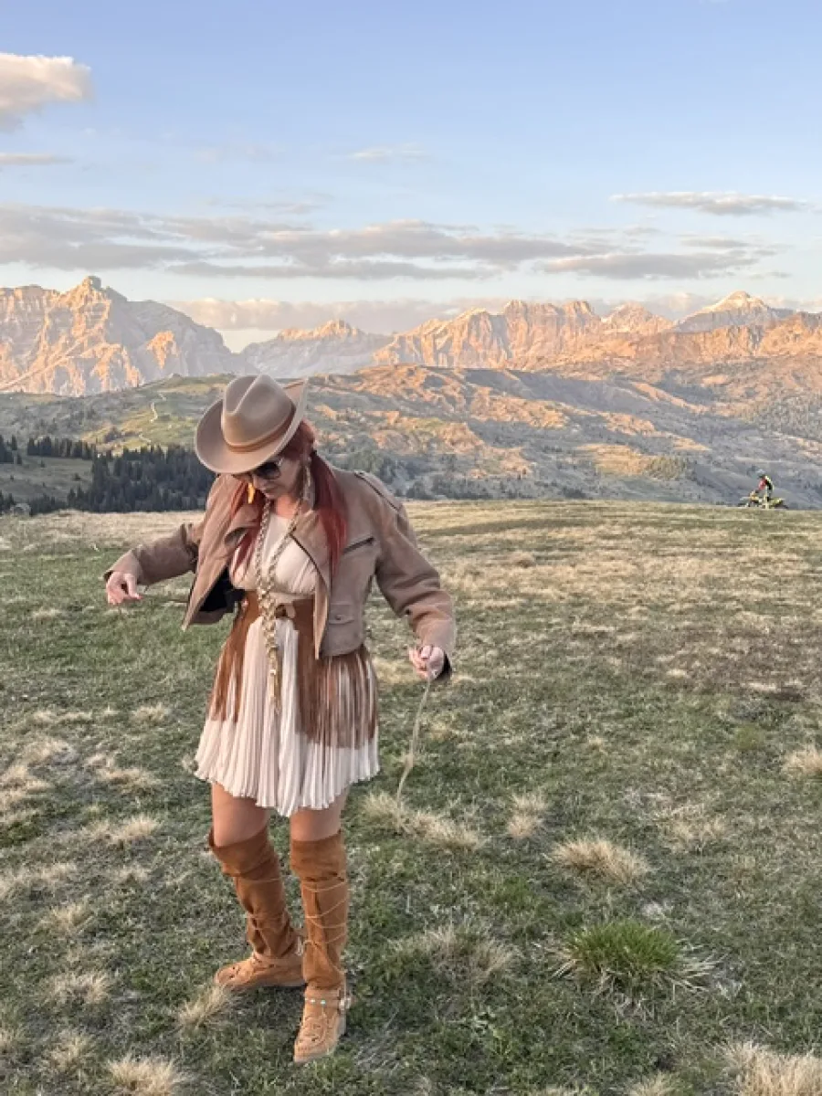 Michaela betrachtet ihr Outfit vor den Südtiroler Bergen