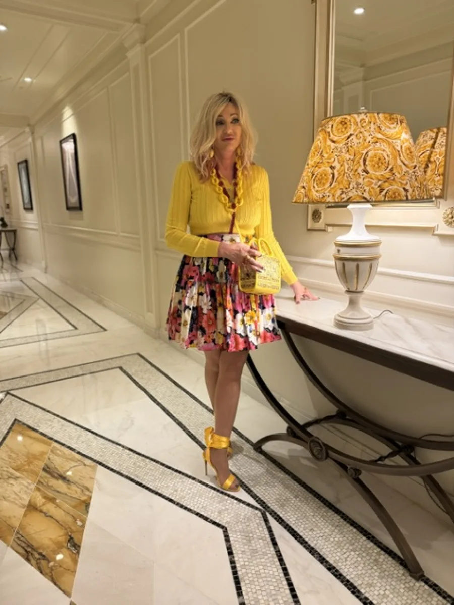 Michaela Hoppe in gelbem Oberteil und floralem Rock mit gelben offenen Schuhen