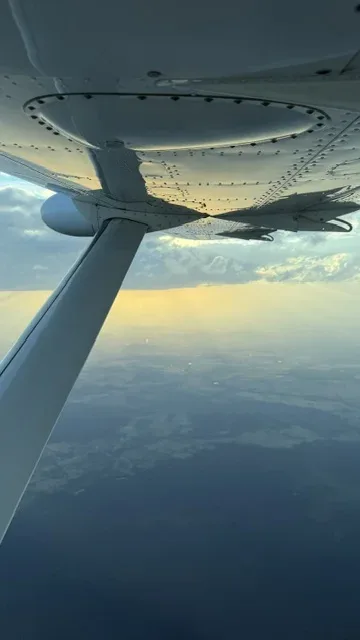 Blick unter dem Flügel auf die Landschaft im warmen Abendlicht