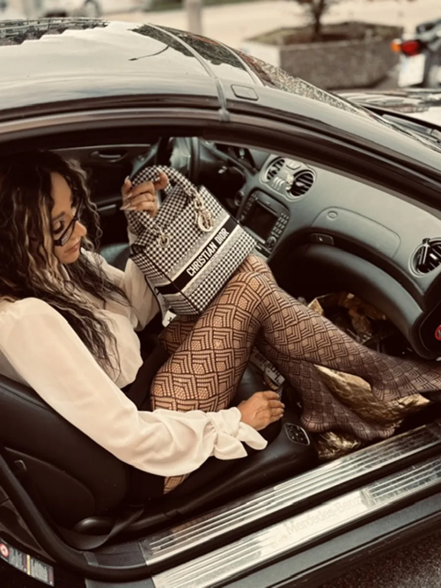 Michaela mit gemusterten Strümpfen, kleiner Tasche und auffälligem Look in einem Auto