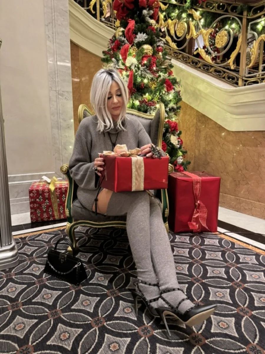 Michaela mit einem Geschenk vor einem geschmückten Weihnachtsbaum