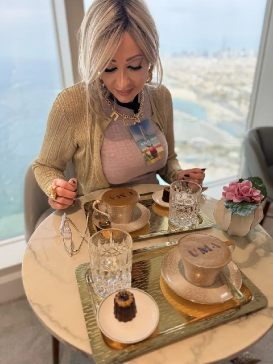 Michaela sitzt im Burj Al Arab vor zwei mit Goldpuder bestäubten Cappuccinos