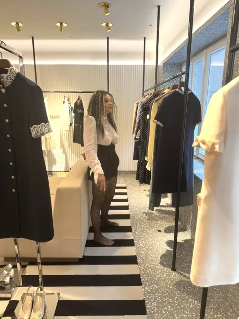 Michi steht zwischen Kleiderständern in einer Boutique