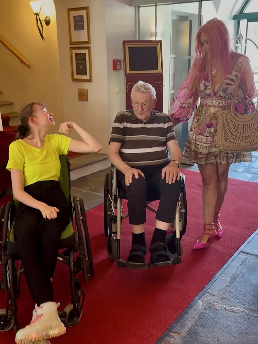 Sarah, Michis Papa und Michaela gemeinsam in einem hellen Eingangsbereich