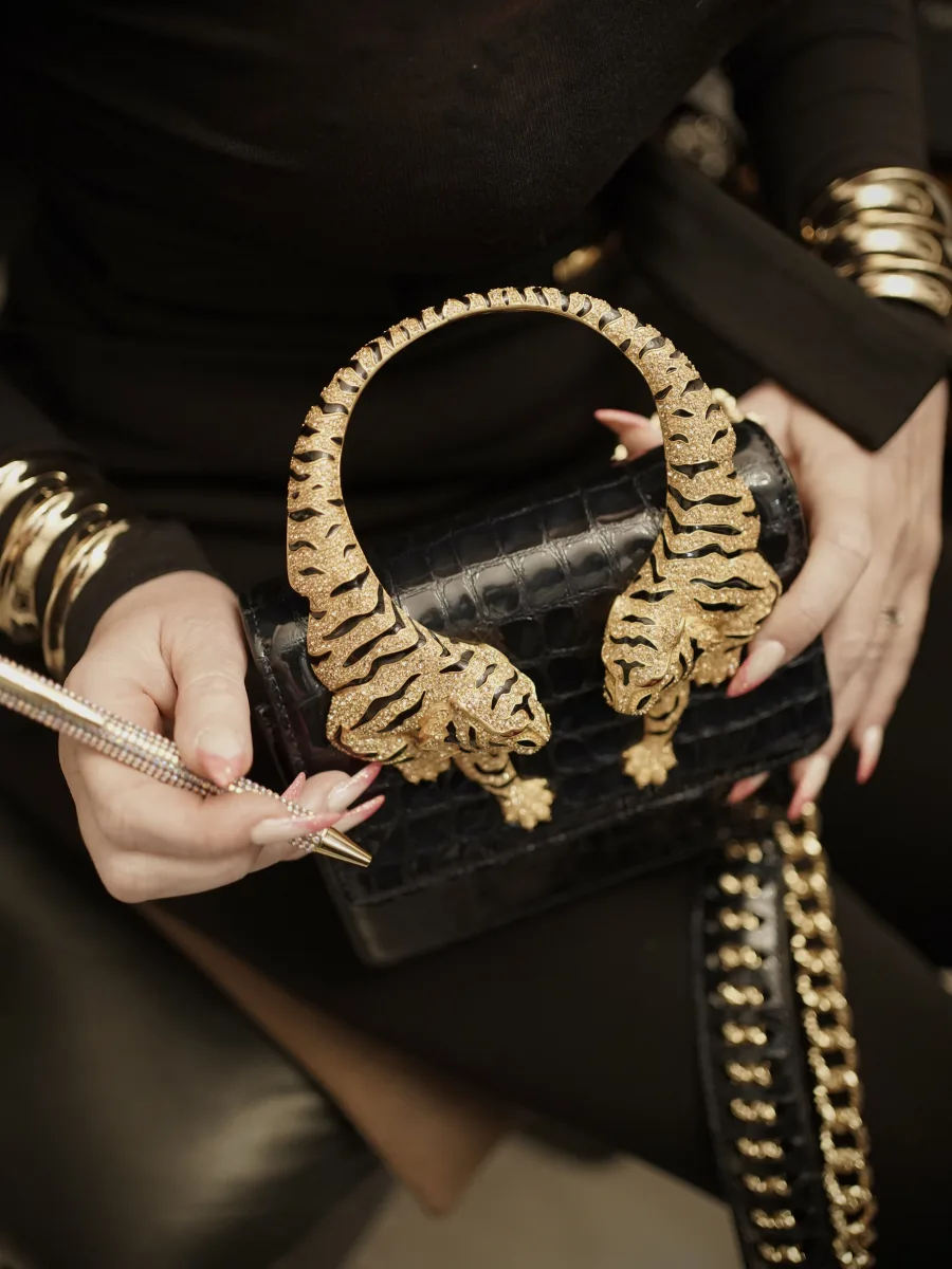 Schwarze Tasche mit zwei goldenen Tigerköpfen und schwerer goldener Kette