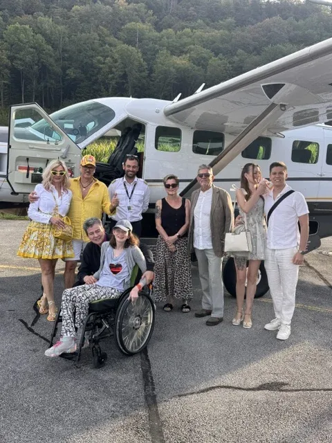 Mehrere Familienmitglieder, darunter Sarah im Rollstuhl, stehen gemeinsam vor dem gecharterten Flugzeug