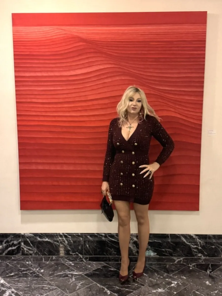 Michi mit blondem Haar vor roter Kunst