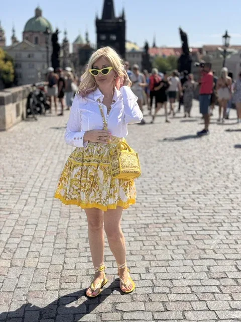 Michi steht in gelbem Dolce-und-Gabbana-Look auf der Karlsbrücke in Prag