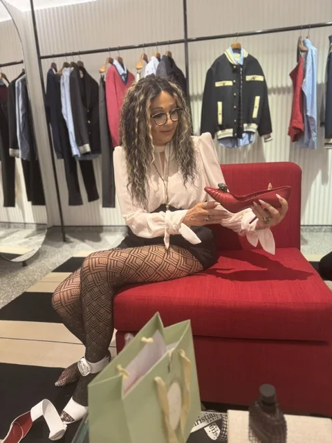 Michi sitzt entspannt auf einem roten Sofa und betrachtet einen roten Schuh