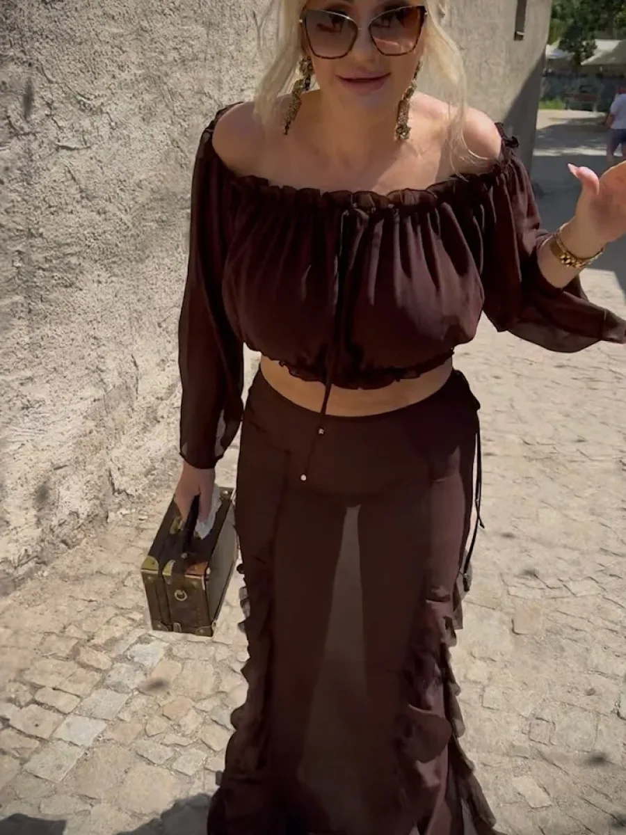 Michaela in einem dunkelbraunen transparenten Zweiteiler mit Rüschen in einer sonnigen Gasse in Krumau