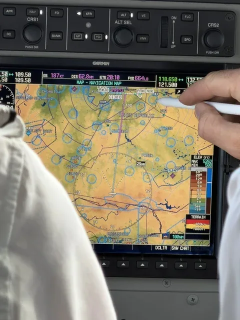 Finger zeigt auf die Flugroute auf dem Navigationsdisplay